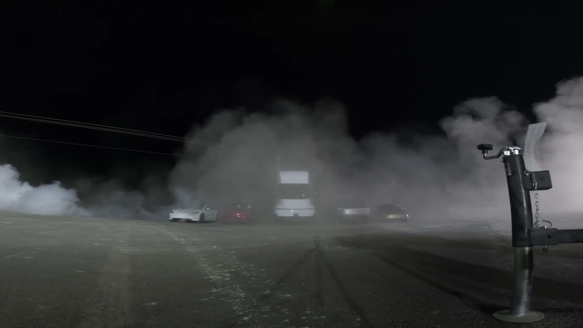 The Tesla lineup in vapor at night after the Roadster's jump — the red Roadster beside the Semi and Cybertruck it leapt over